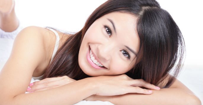 Young woman smiling and resting her head on her arms
