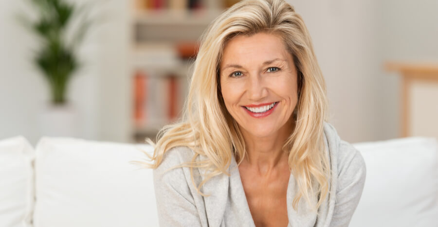 Mature woman with blonde hair smiling on a couch