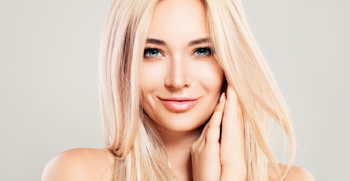 Young blonde woman with glowing skin and long hair smiling