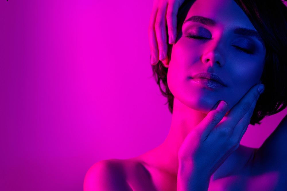 Relaxed woman with closed eyes bathed in pink and blue light