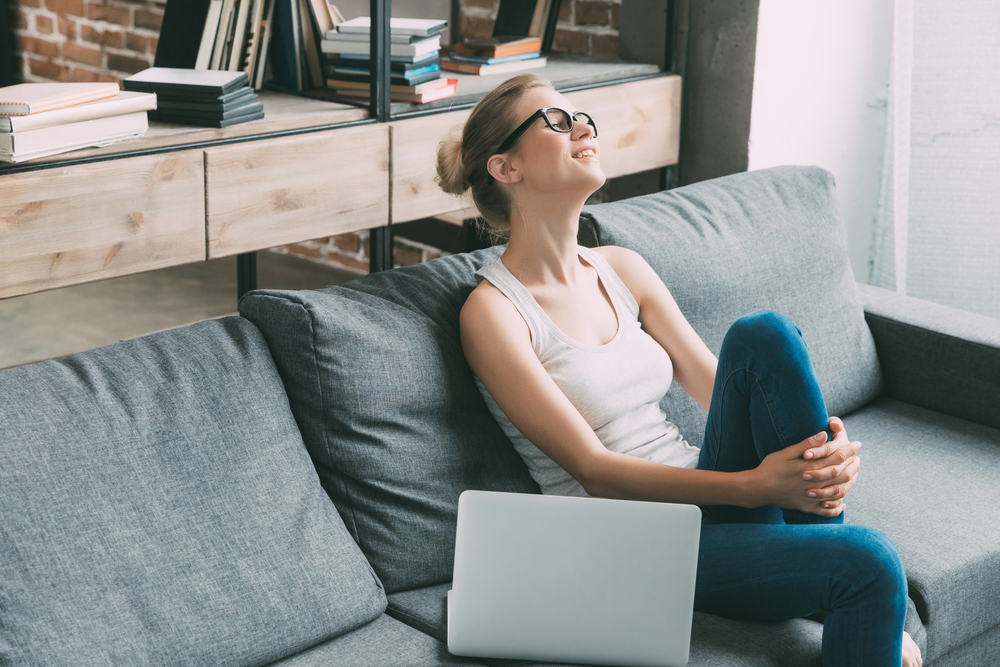 Woman relaxing on her couch next to a laptop