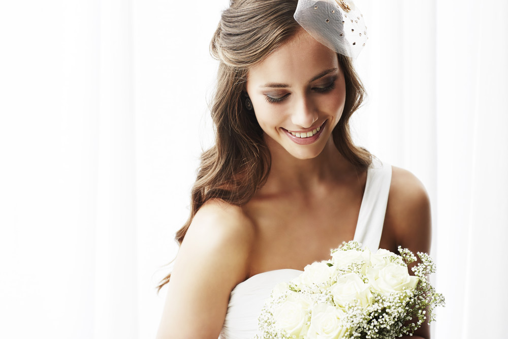 Bride with long brown hair holding a bouquet and smiling