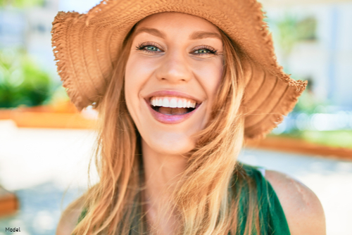 Confident woman with long blonde hair wearing a straw hat and smiling outdoors
